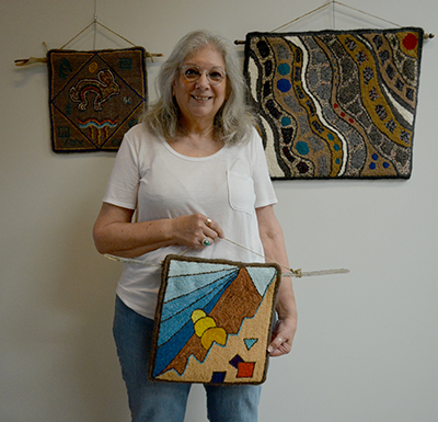 Rug artist Beth Soucie with three of her pieces. Photo by Raquel Hendrickson