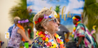 A woman wears sunglasses, a Hawaiian shirt, leis and a grass skirt as she walks through the Maricopa Community Center on July 26, 2023. The center celebrated its second anniversary with a potluck luau. [Monica D. Spencer]