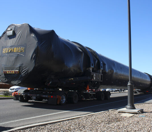 An oversized load carrying a SpaceX rocket travels down Honeycutt Road towards John Wayne Parkway on Feb. 21, 2024. Engine outlines can be seen on the back of the truck carrying the load. [Jeff Chew]